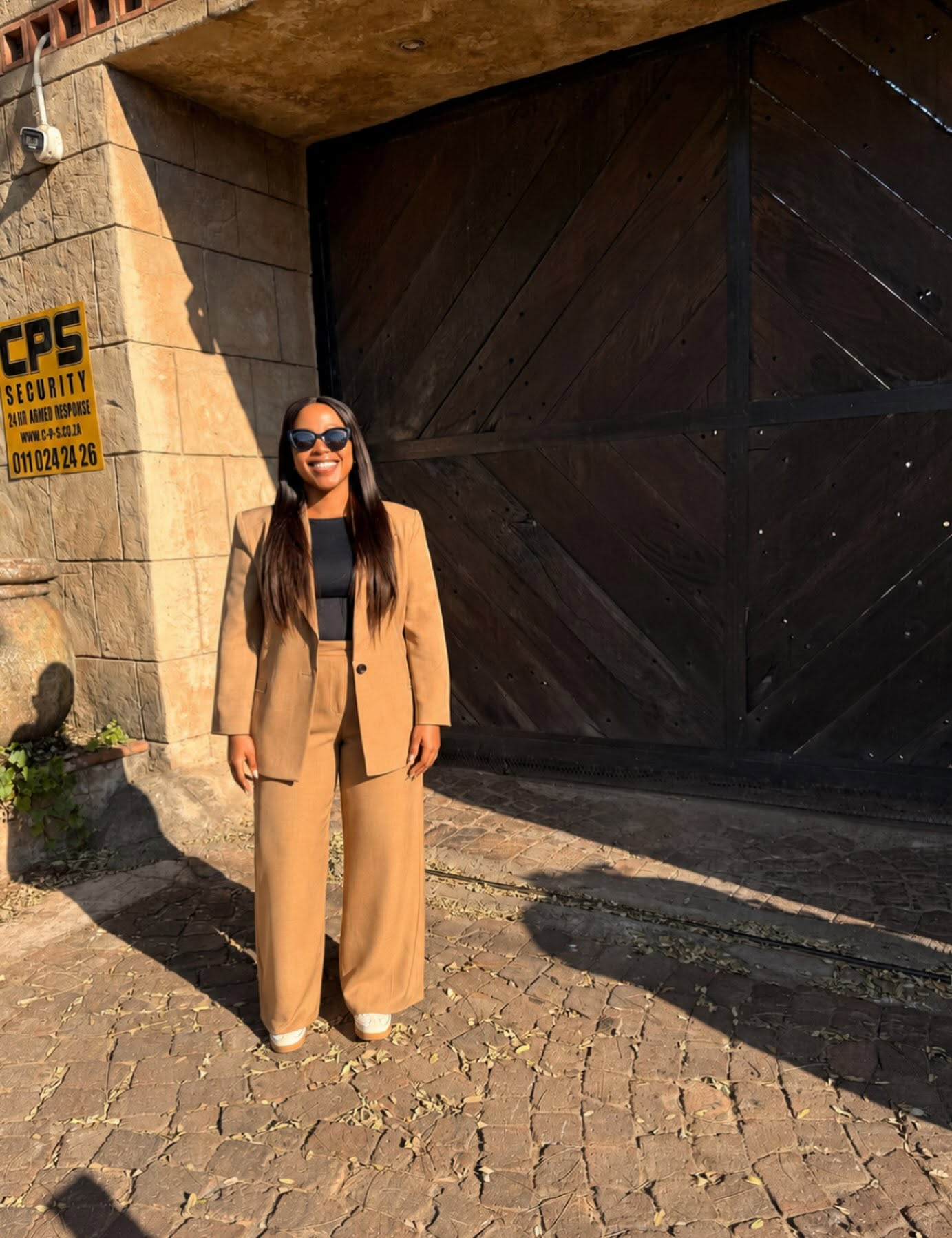 Nandisa outdoors in a tan suit and sunglasses