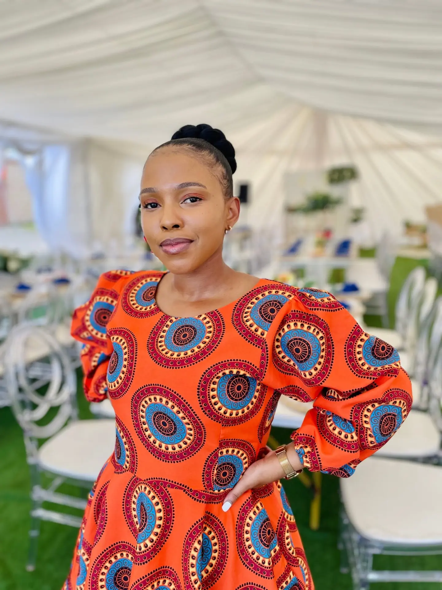 Nandisa wearing an orange patterned dress at a celebration